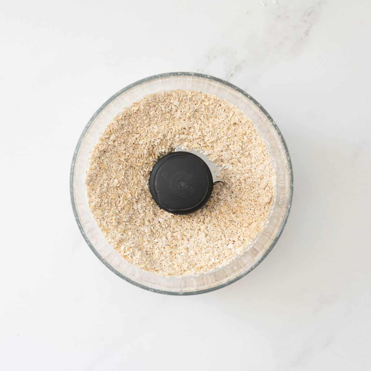 Ground rolled oats in a food processor bowl. 