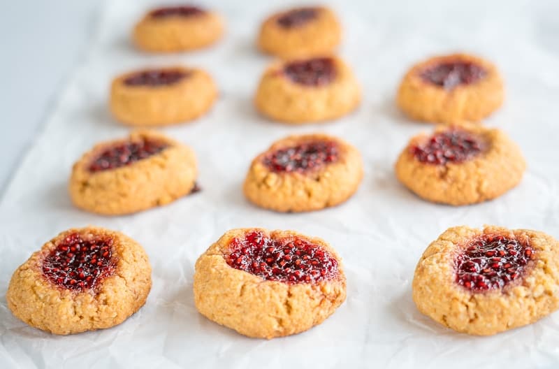 Raspberry jam thumbprint cookies on a line bakong tray.