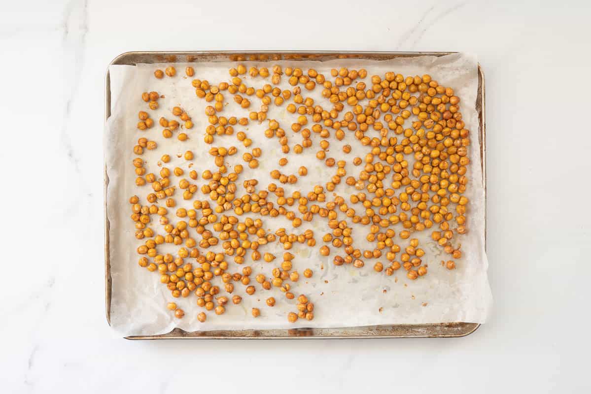Golden roasted chickpeas in a baking lined roasting tray.