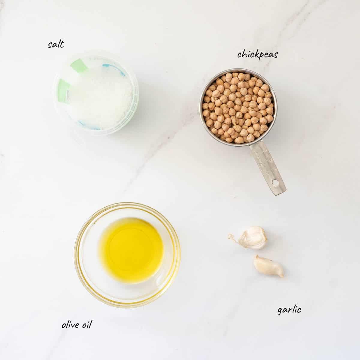 the ingredients to make garlic roasted chickpeas laid out on a bench top with text overlay.