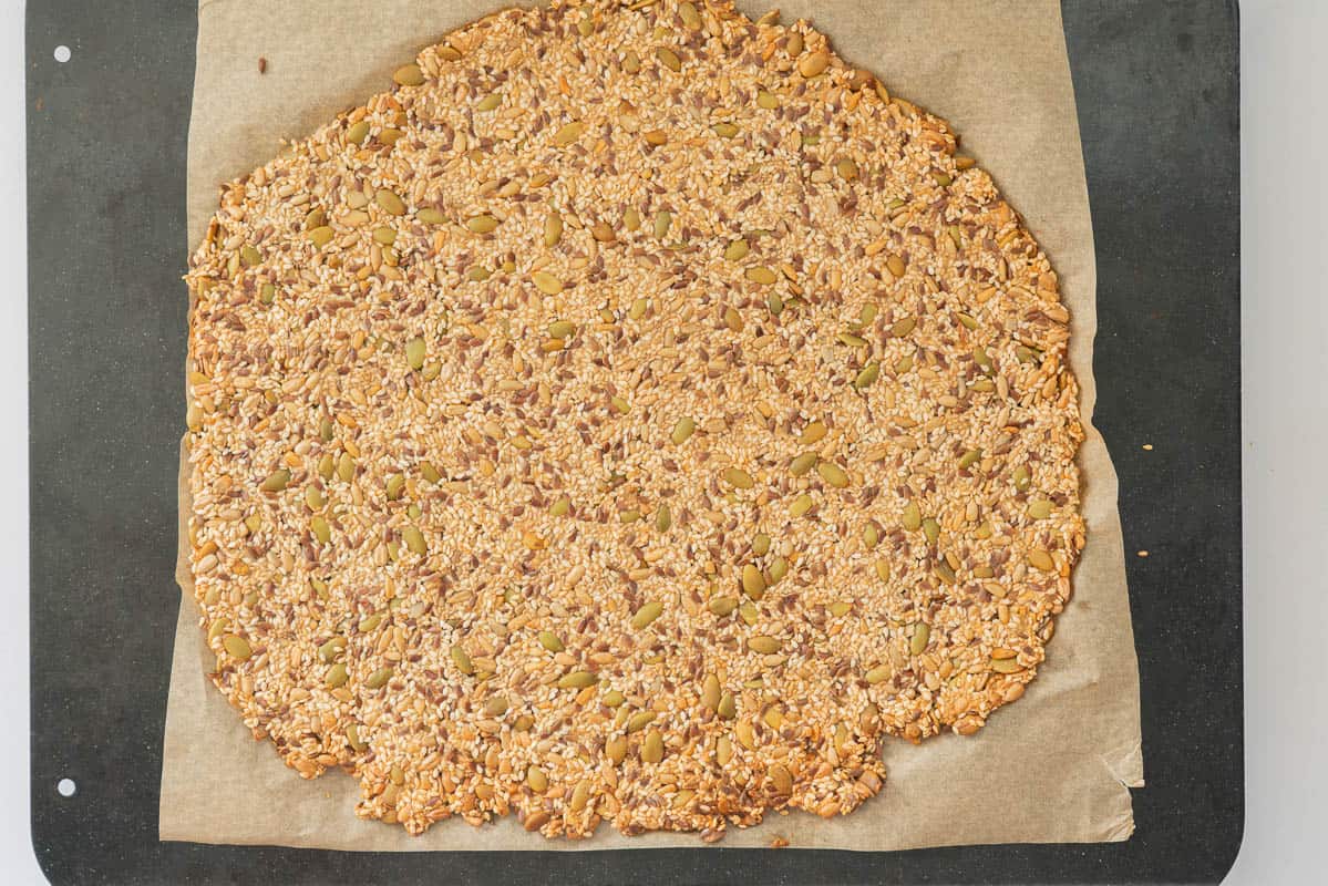 A slab of seed cracker mix, baked, golden and ready to be sliced into cracker shaped pieces. 