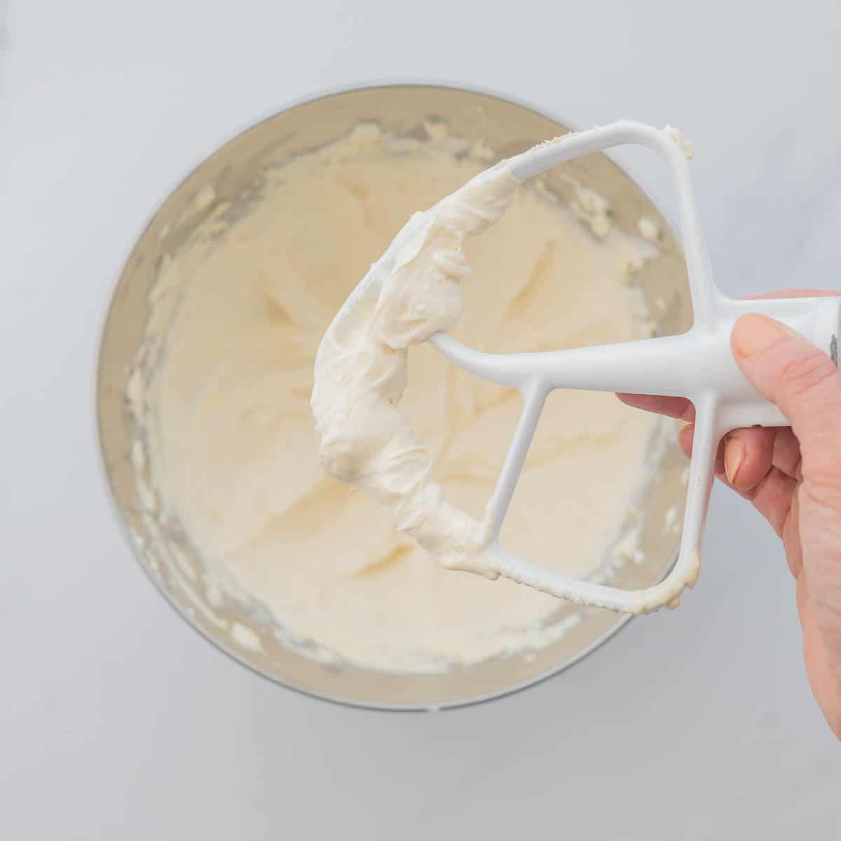 Cream cheese frosting on the beater attachment of a stand mixer. 