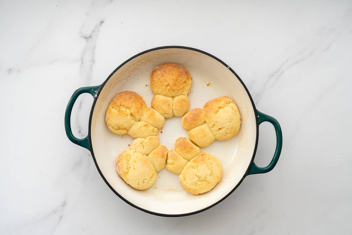 Five golden baked bunny buns in a white enamel cast iron dish.