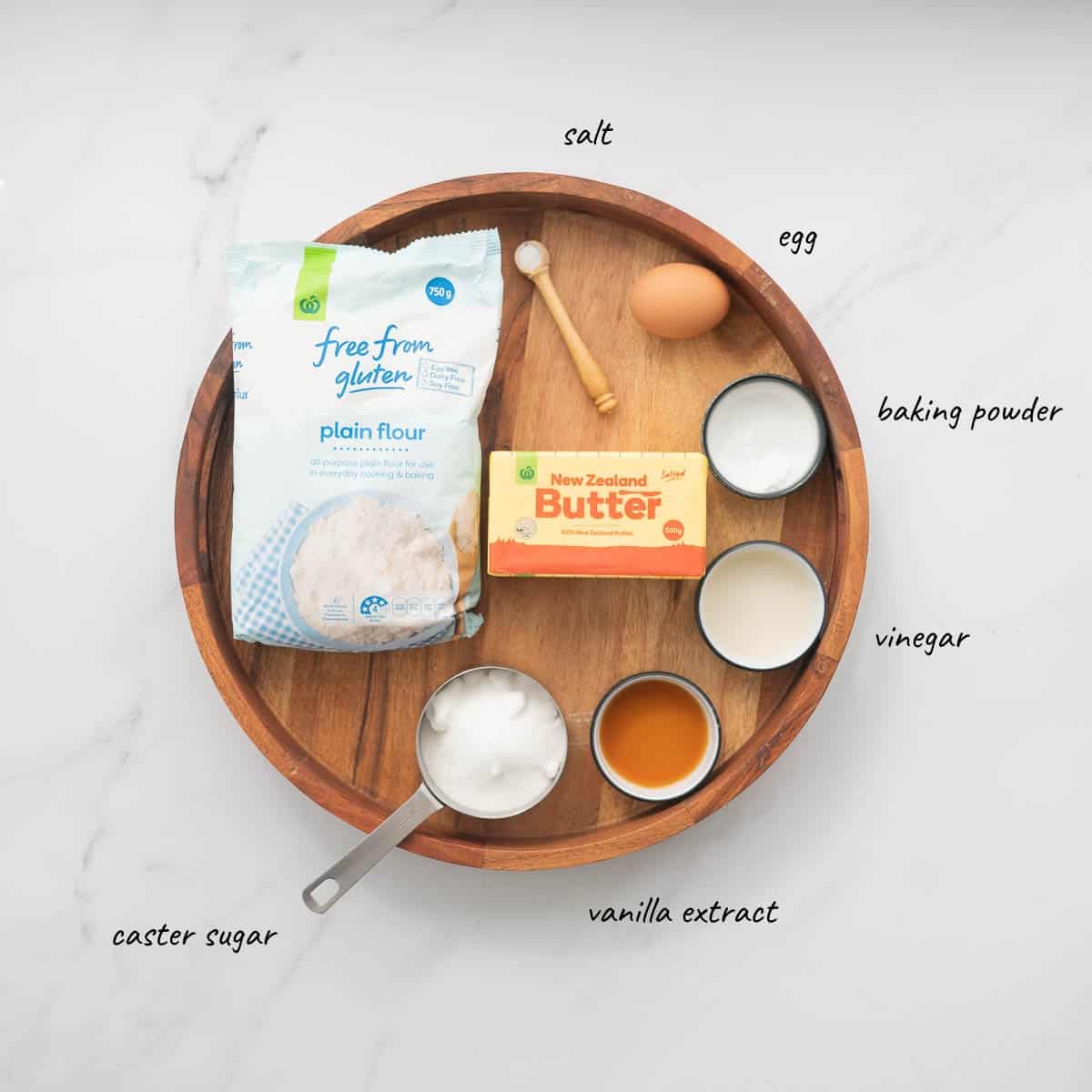 The ingredietns to make Gluten Free sugar cookies on a round wooden tray with text overlay.