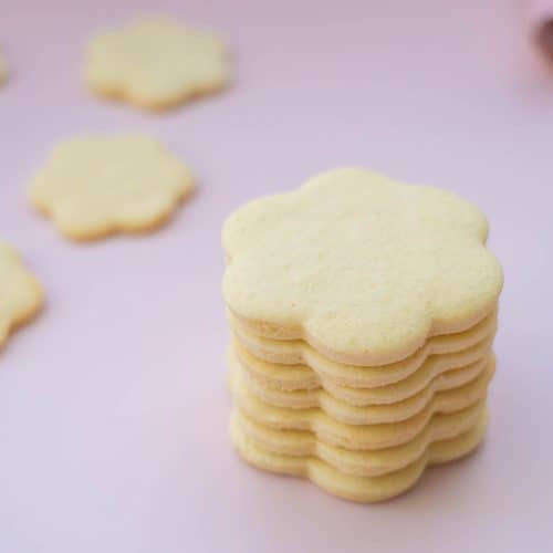 A tower of flower shaped cookies on a pink background