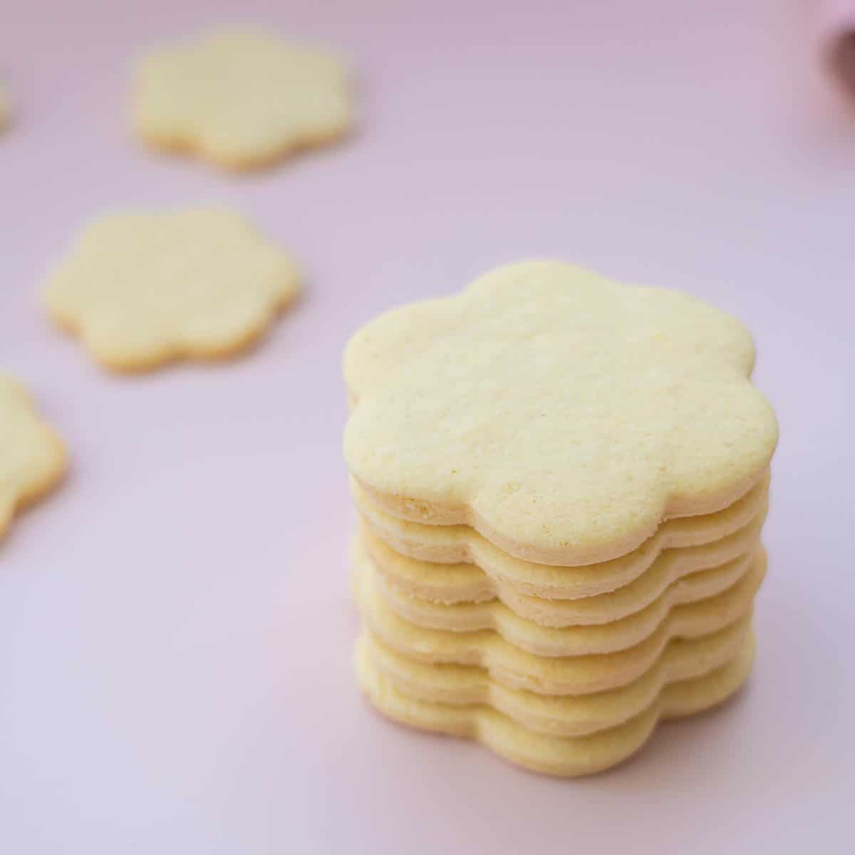 A tower of flower shaped cookies on a pink background