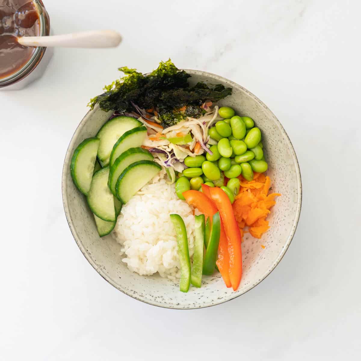 Rice, vegetables and toasted seaweed in a ceramic bowl.