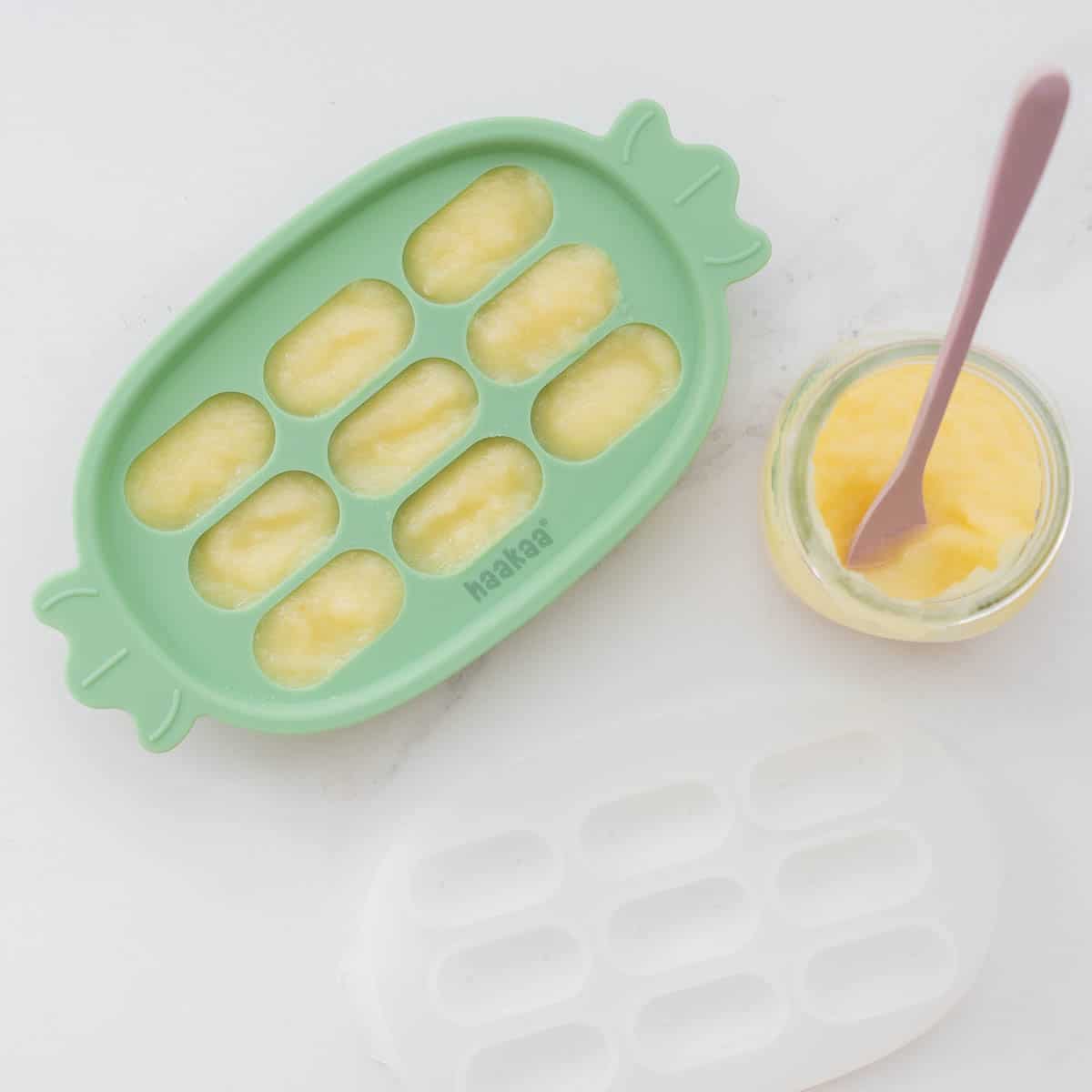 Applesauce portioned into a green silicone baby food freezer tray.