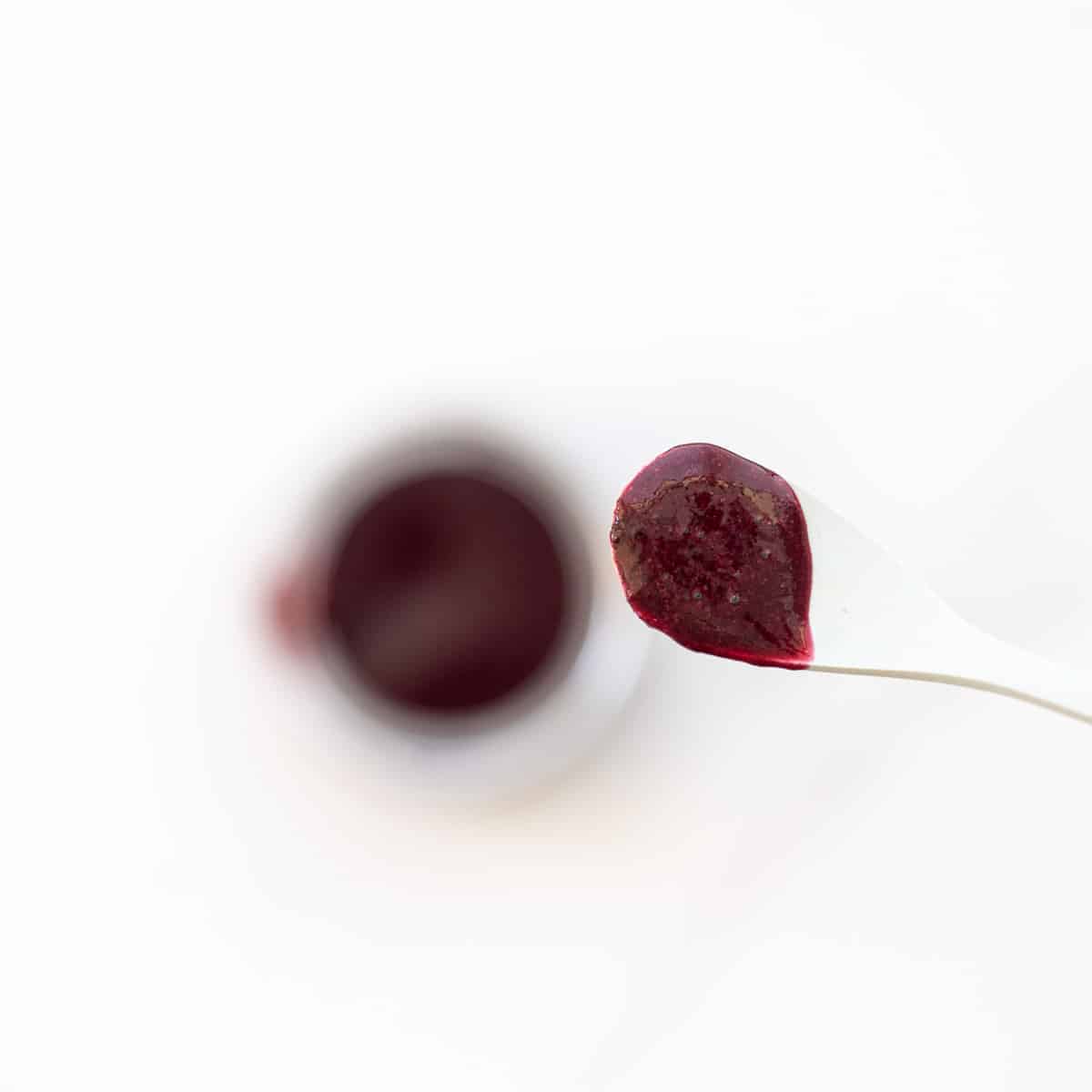 A spoonful of blueberry puree being held up to the camera. 