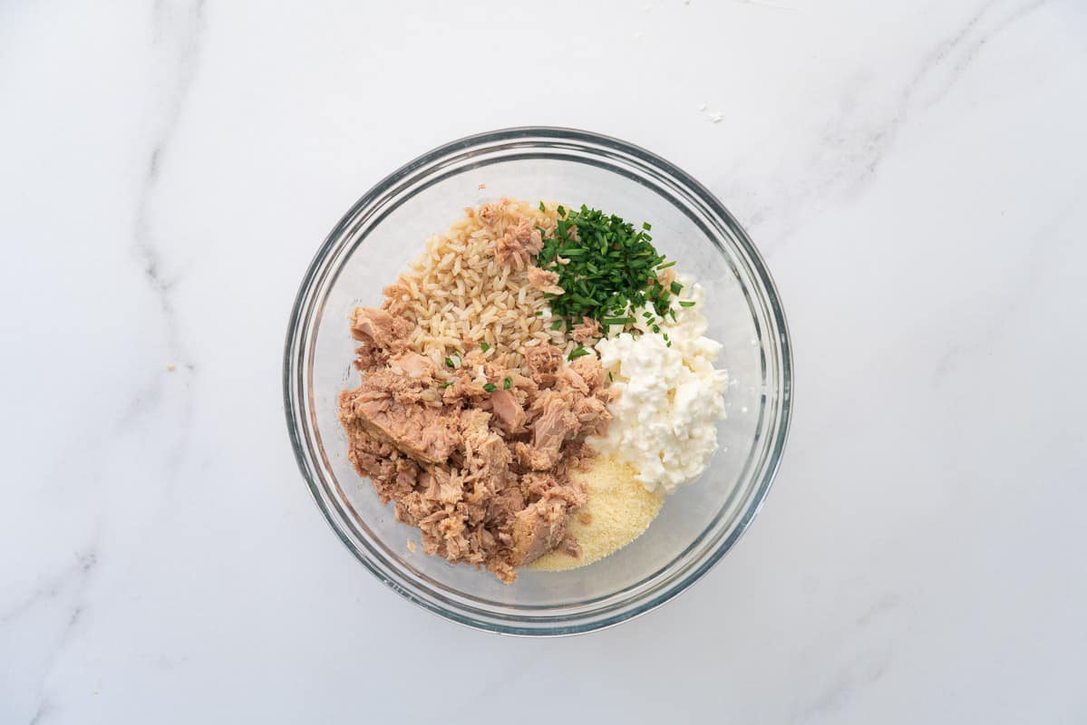 Brown rice, canned tuna, cottage cheese and chives in a glass mixing bowl.  Ready to be mixed. 