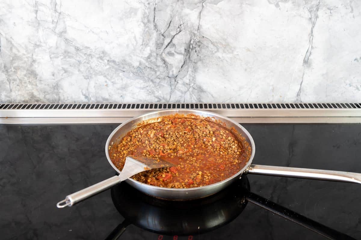 Lentil bolognese simmering on a stove top.