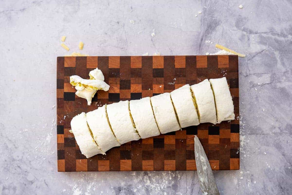 A log of pizza dough and fillings sliced into 8 scrolls. 
