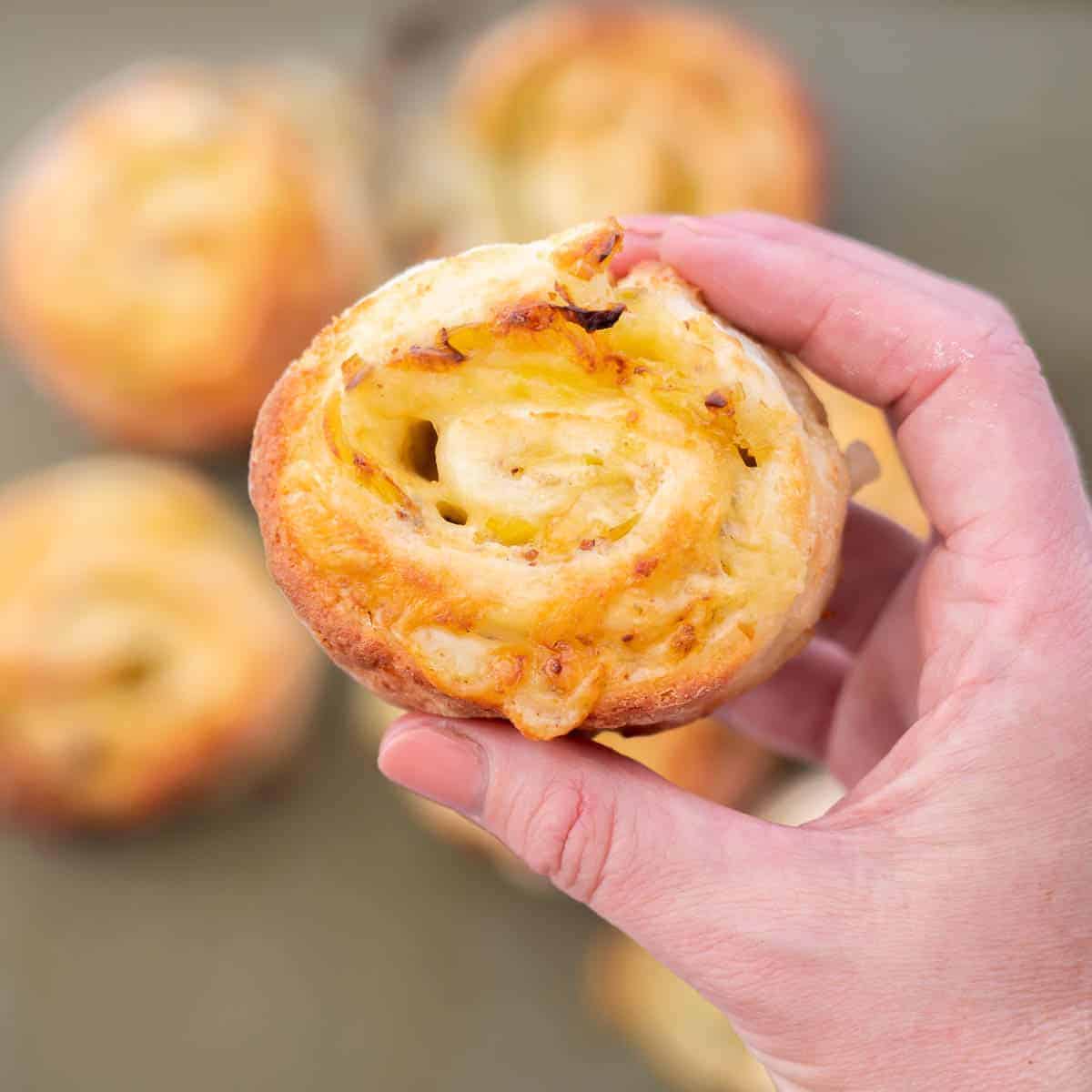 A golden baked pinwheel being held up to the camera.