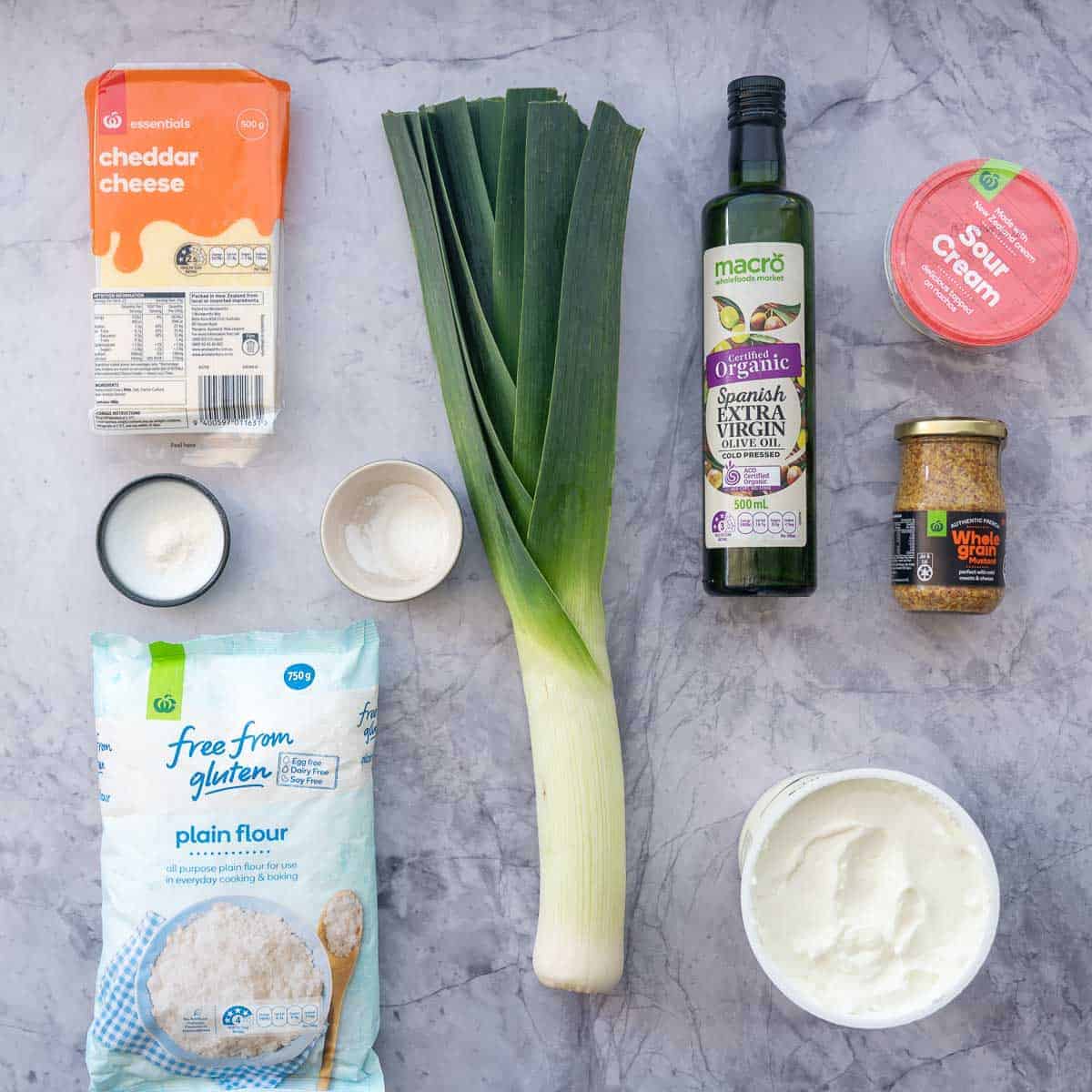 The ingredients to make a gluten free pizza dough with cheese and leek filling laid out on a marble bench top.