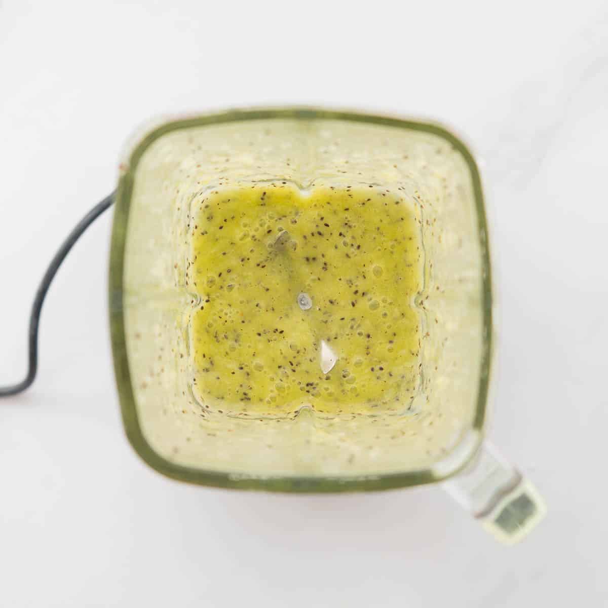 Kiwifruit puree in the bottom of a square glass blender jug.