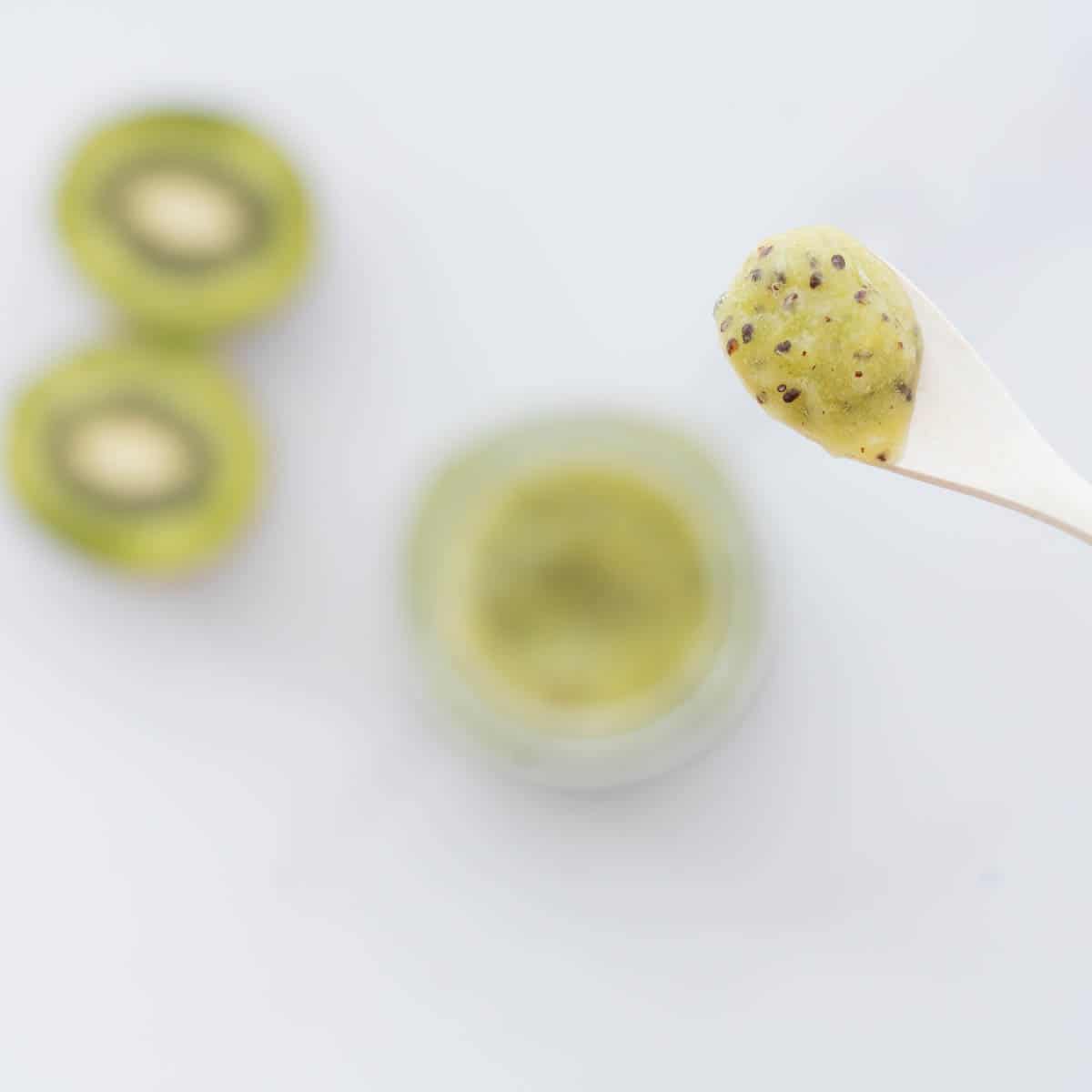 A spoonful of kiwi puree on a white bamboo spoon.
