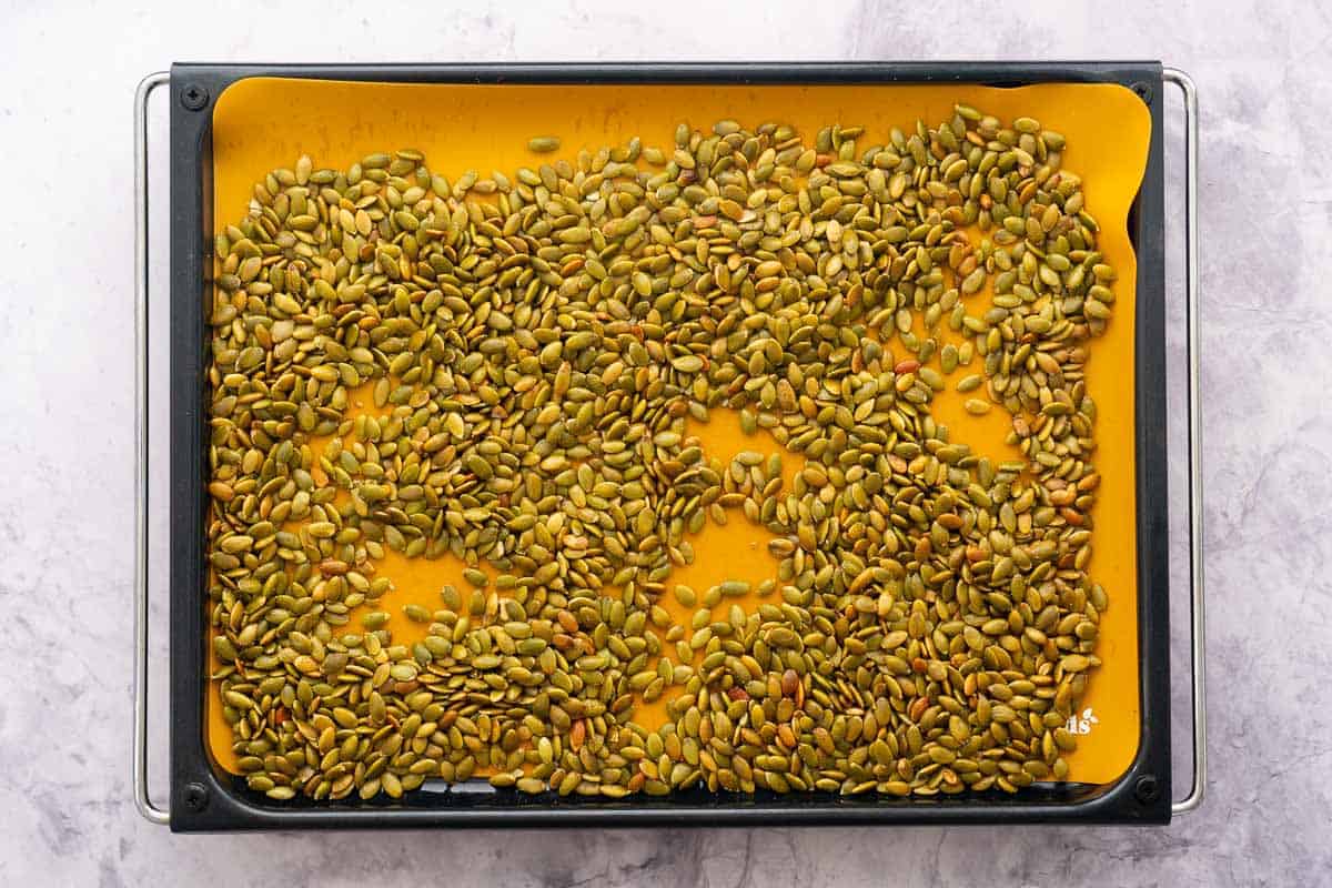 Toasted pumpkin seeds on a lined baking sheet.
