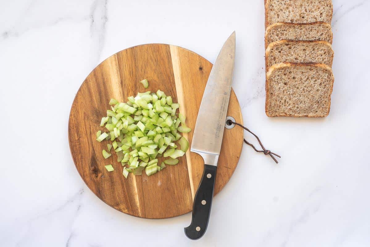 Diced celery on a round wooden chopping board. 