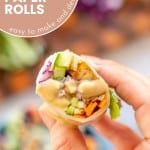 A veggie filled fresh spring roll drizzled in satay sauce being held up to the camera with text overlay for pinterest.