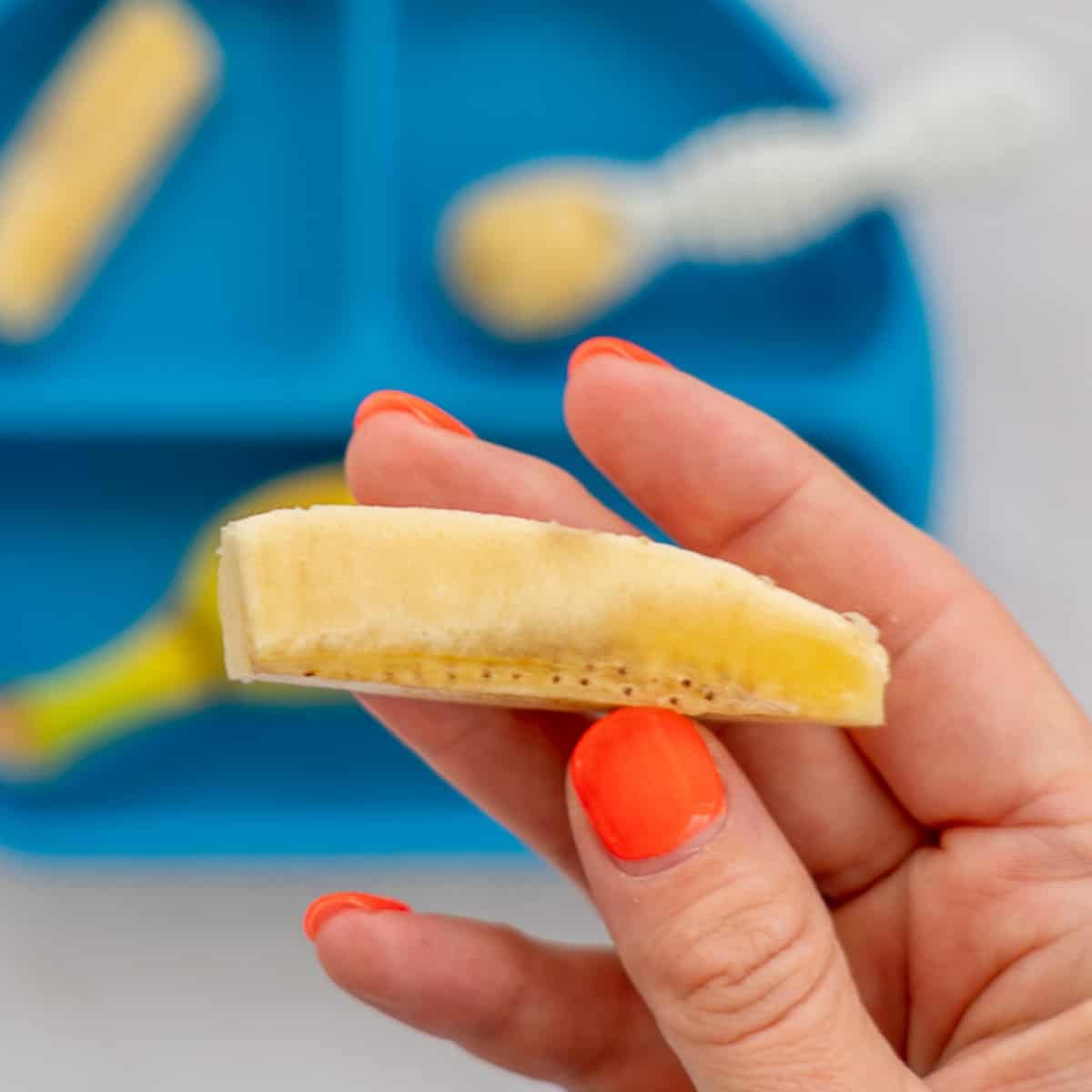 A piece of banana cut into a baton being held 