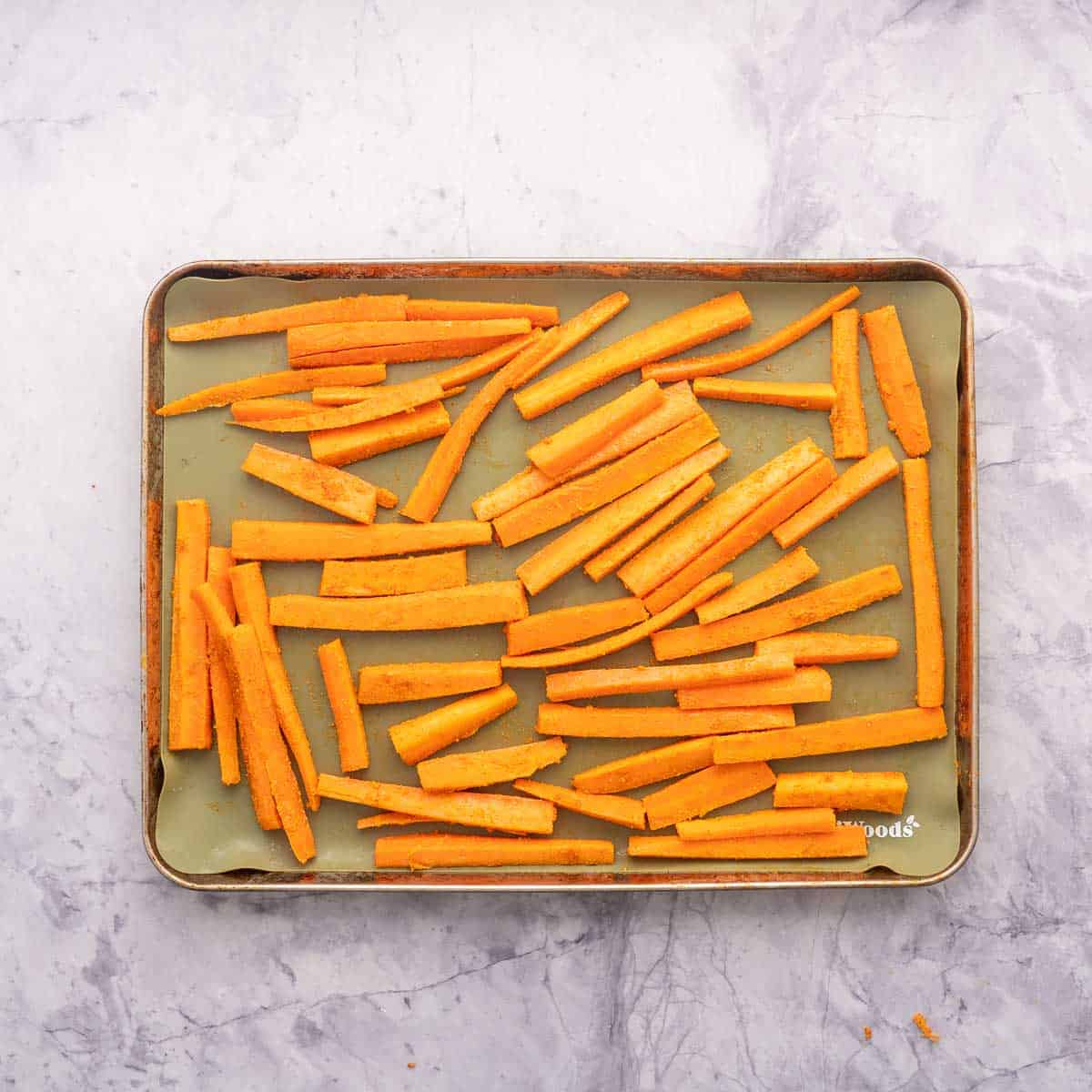 Carrot sticks on a lined baking sheet ready to go into the oven.
