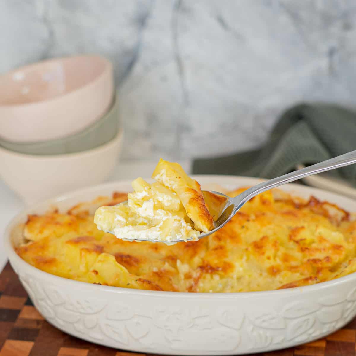 Scalloped potatoes being served with a large spoon.