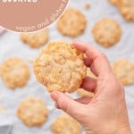 A coconut cookie being held up to the camera with text overlay for pinterest