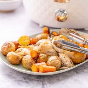 A platter of roast chicken and vegetables in front of a slow cooker