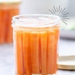 A jar of pickled carrots on a bench top with text overlay for pinterest.