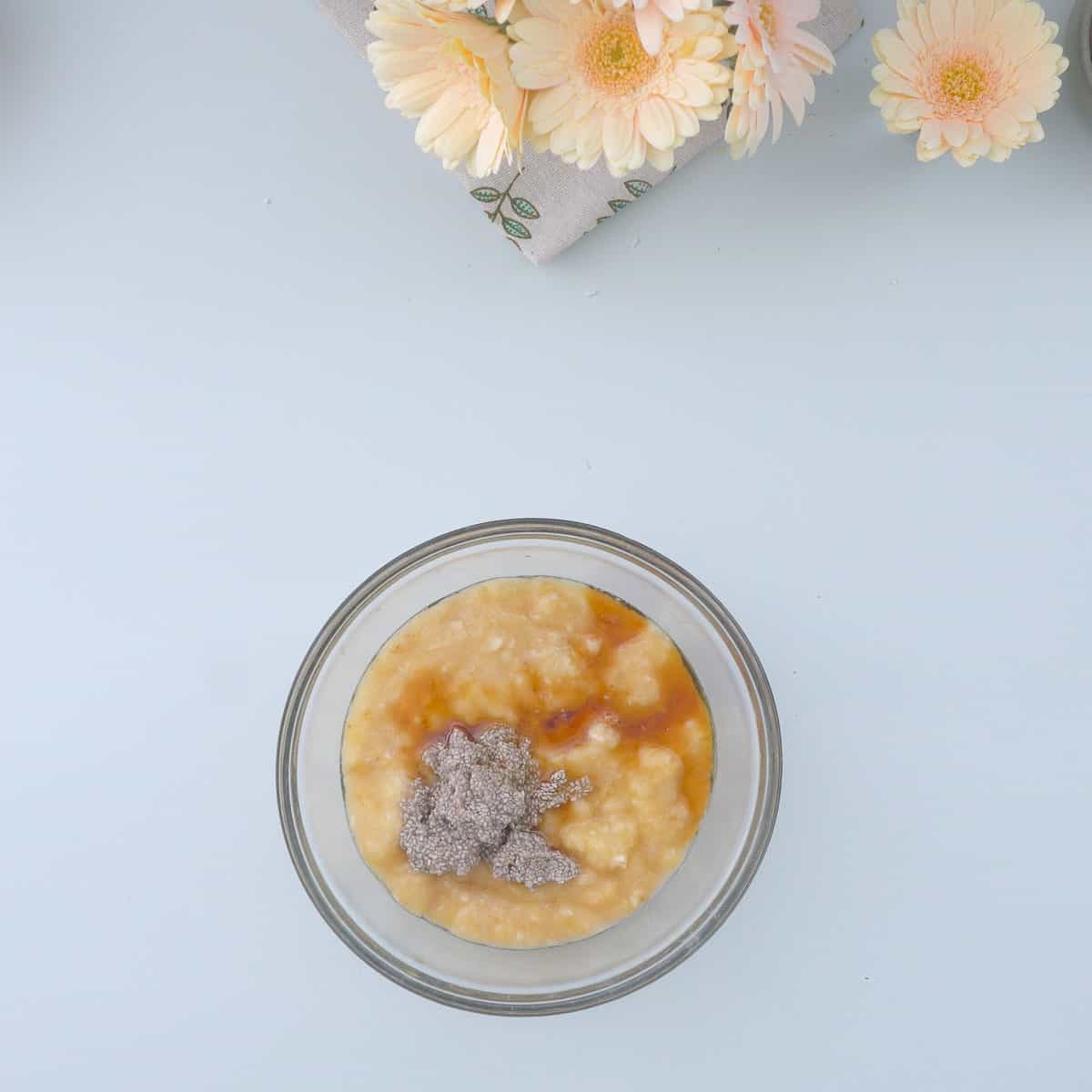 A glass mixing bowl of mashed banana, chia seeds and vanilla extract. 