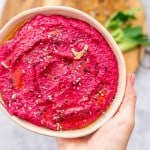 A bowl of bright magenta hummus being held up to the camera