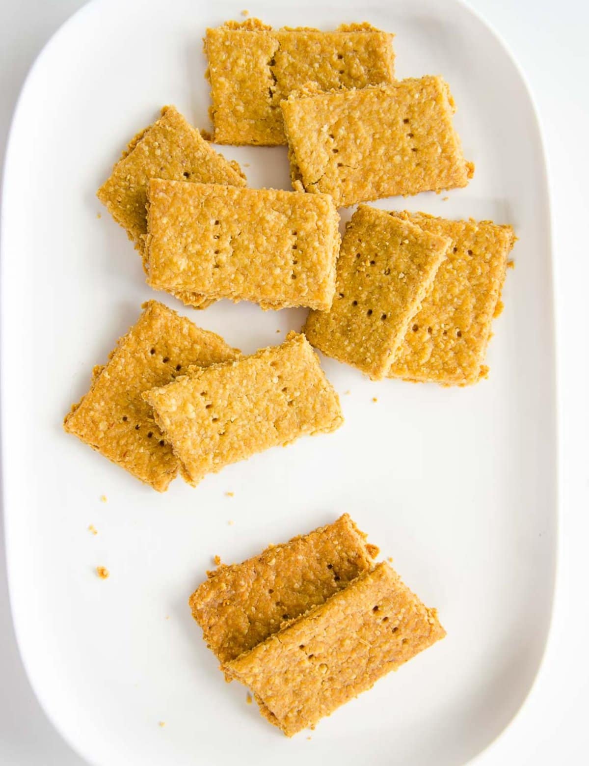 A white ceramic plate scattered with crackers. 