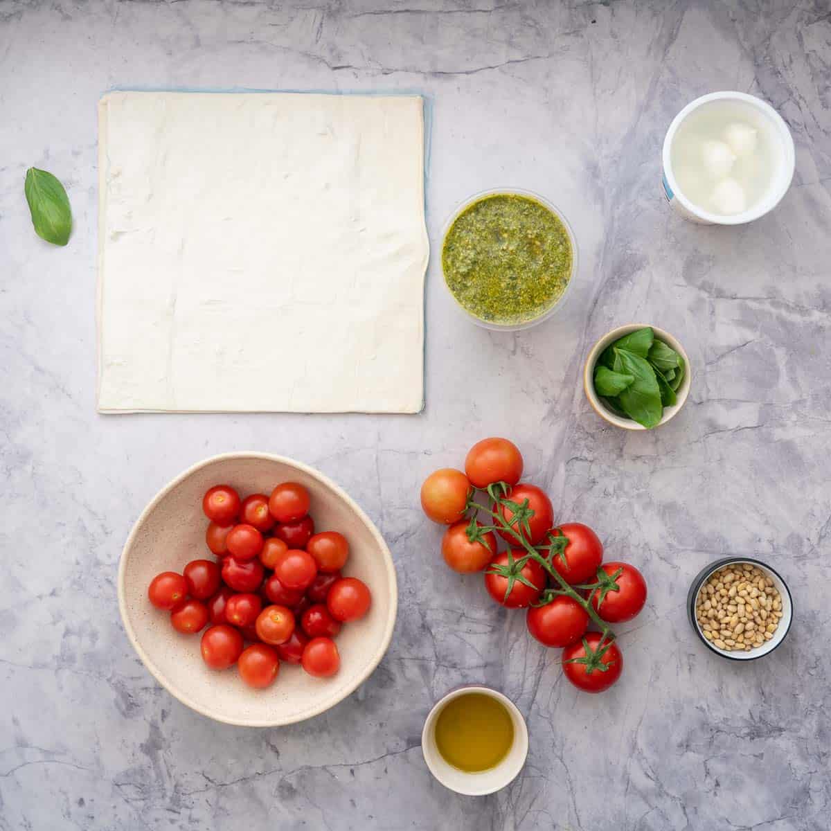 ingredients for the Tomato Tart laidout on the bench - one sheet of puff pastry, tomatoes, pesto, pine nuts, cheese and basil 