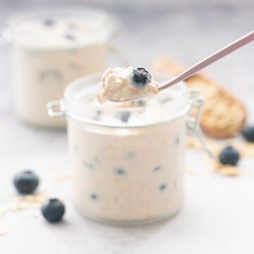 A spoonful of blueberry overnight oats being scooped out of a small jar.