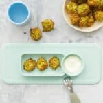 Three broccoli tots on a baby silicone plate.