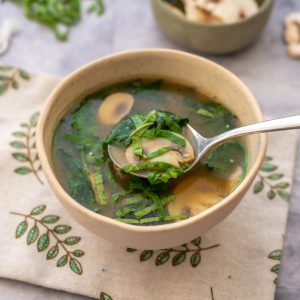 a bowl of miso soup with chicken and vegetables floating in the broth with text overlay for pinterest