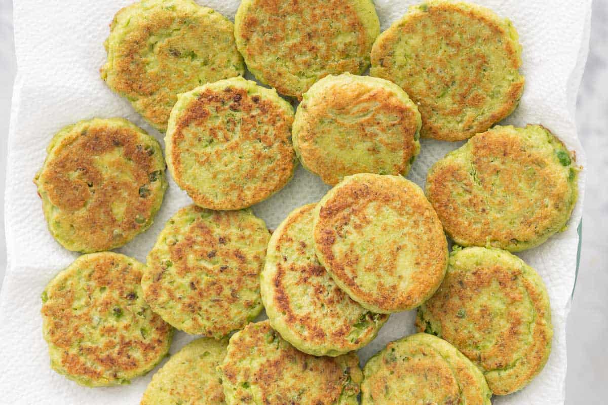 Golden pea fritters laid out on a sheet of paper towel
