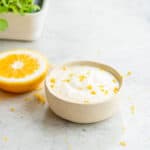 A small ramekin filled with a feta dip topped with grated lemon zest.