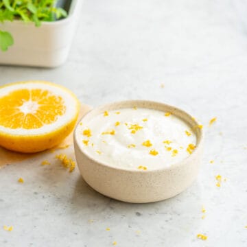 A small ramekin filled with a feta dip topped with grated lemon zest.