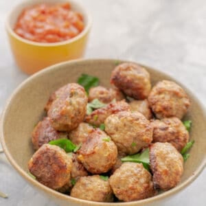 A bowl of meatballs garnished with chopped parsley