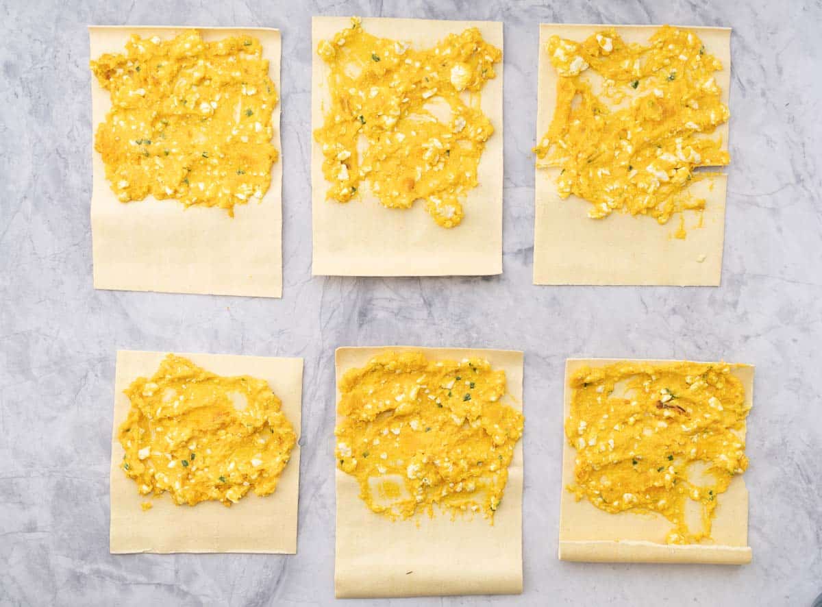 fresh pasta sheets laid out on the bench top and spread with butternut cottage cheese pasta filling.