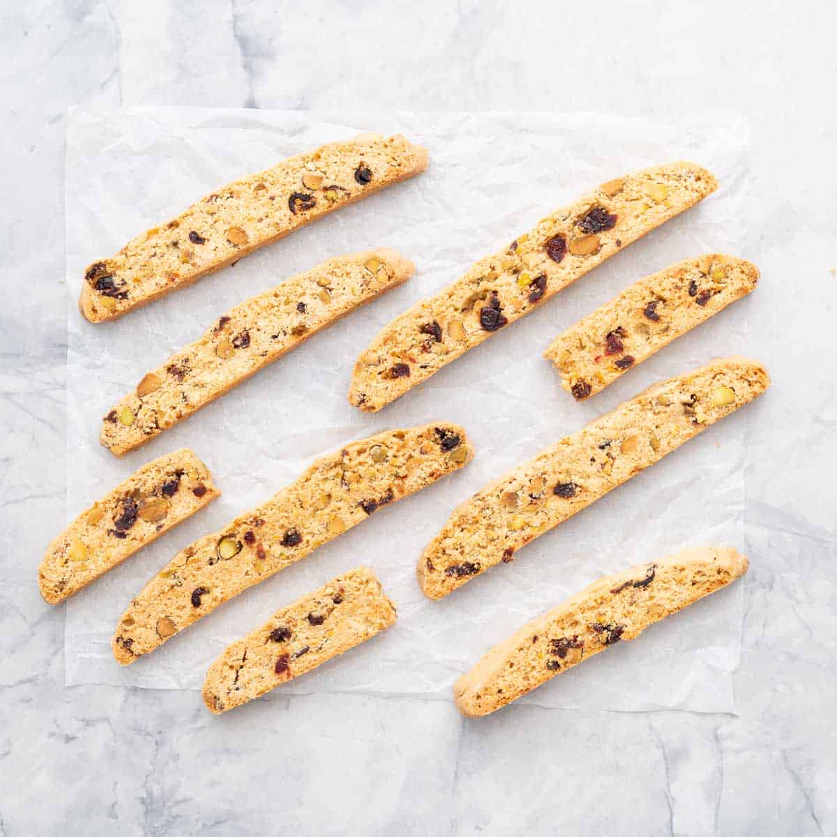 Pieces of biscotti studded with fruit and nuts on a crinkled piece of white parchment paper. 