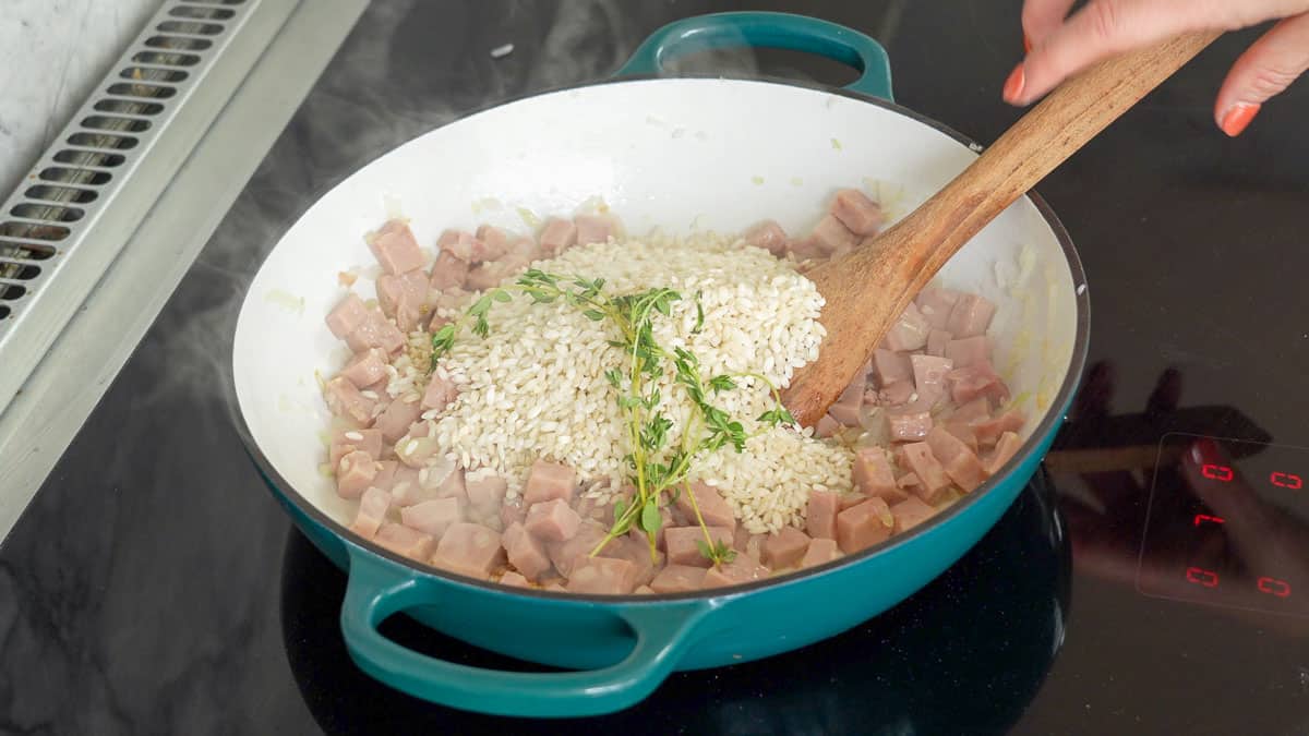 Arborio rice and diced ham in a pan