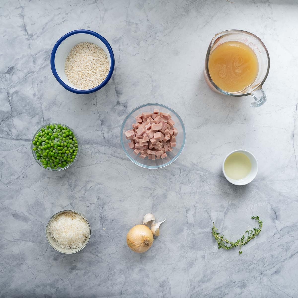The ingredients to make pea risotto with ham laid out on a marble bench top