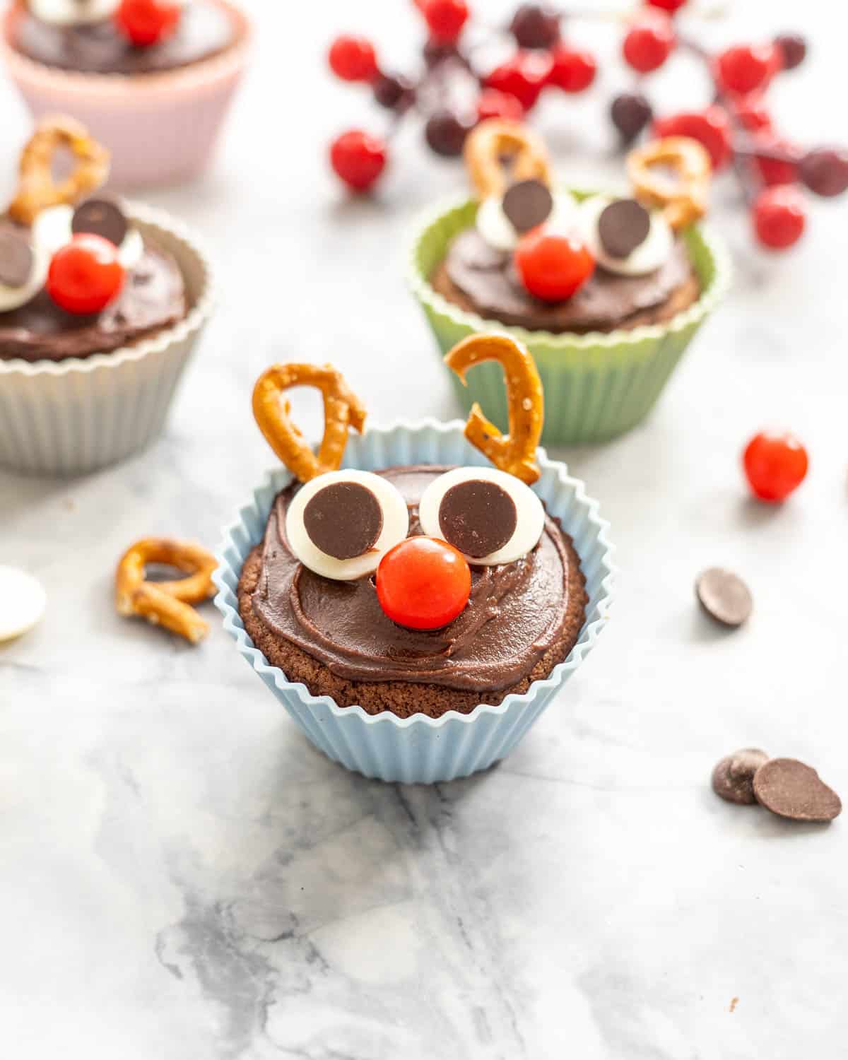 A cupcake decorated like a reindeer in a blue cupcake liner. 
