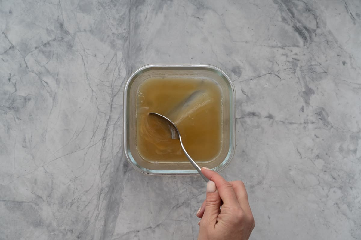 A spoon making a channel in a brown gel.
