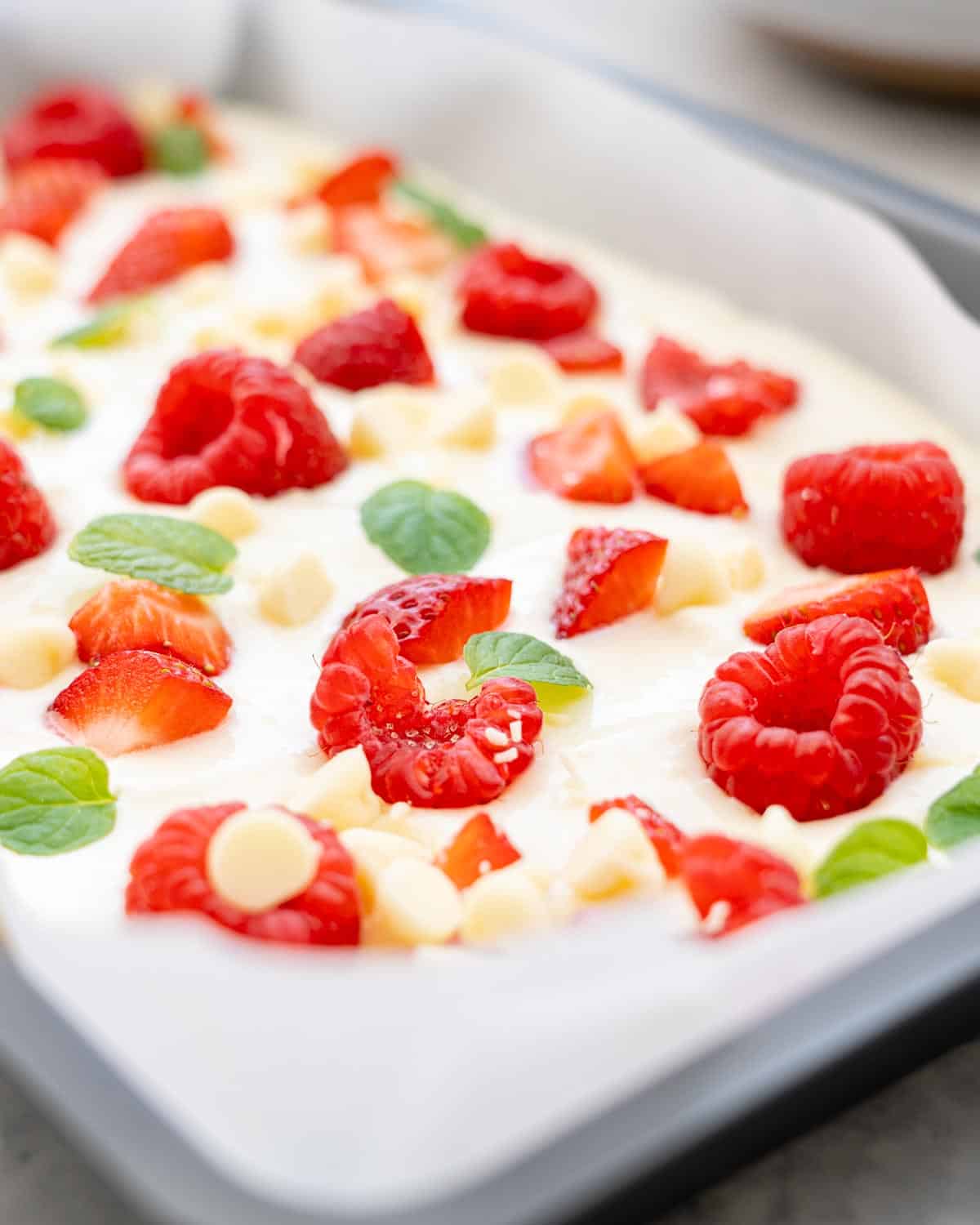 A close up of the yoghurt bark which has a scattering of raspberries, strawberries and choclate drops 