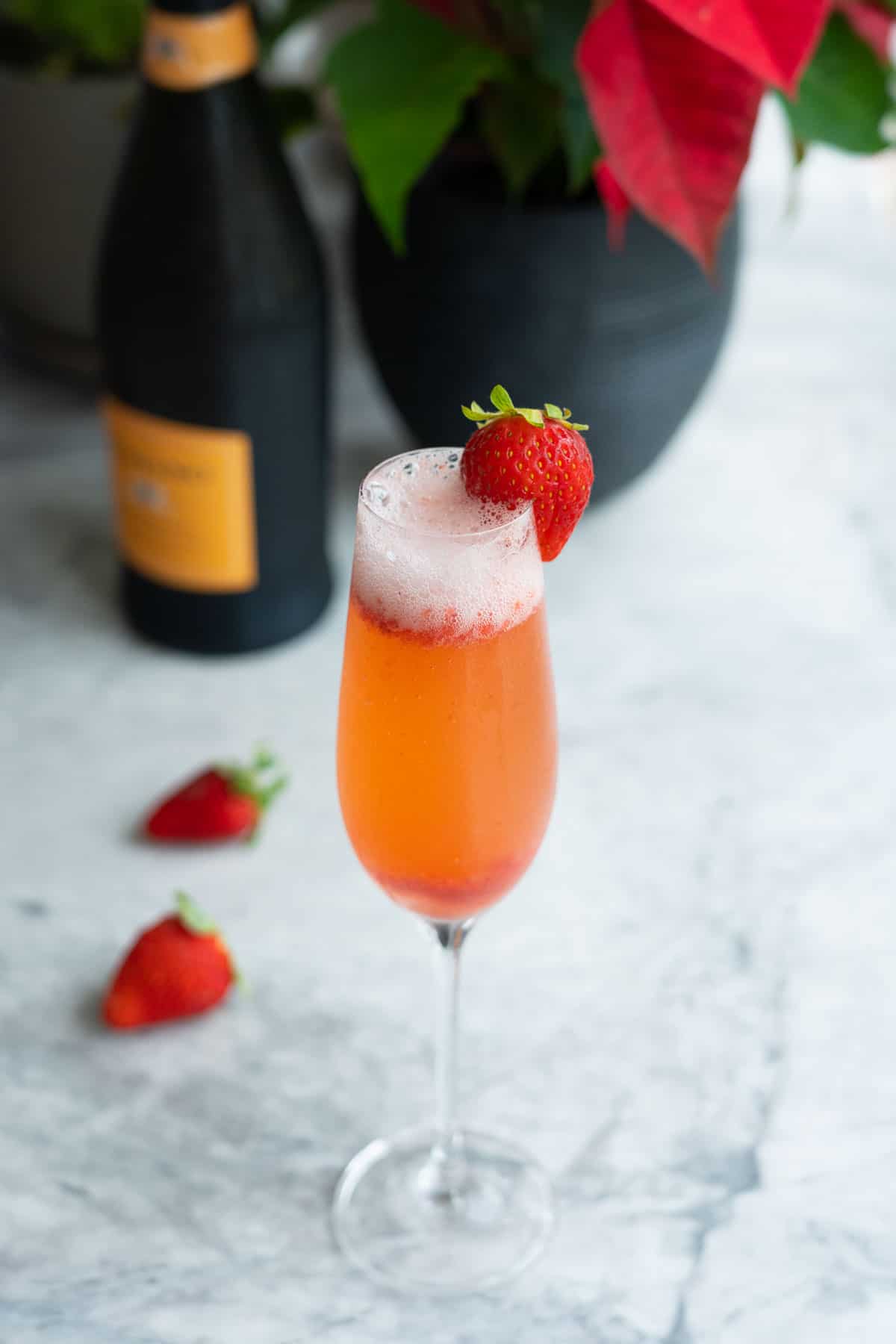 A champagne flute of rossini cocktail garnished with a strawberry on the rim of the glass.