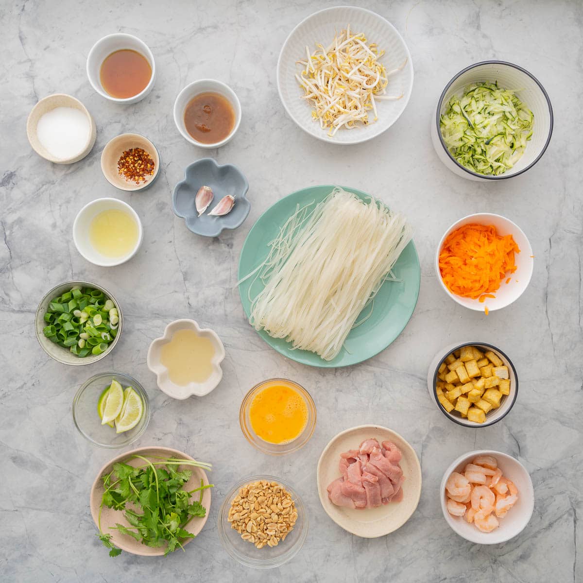 Ingredients to make a pad Thai stir fry laid out on a bench top. 