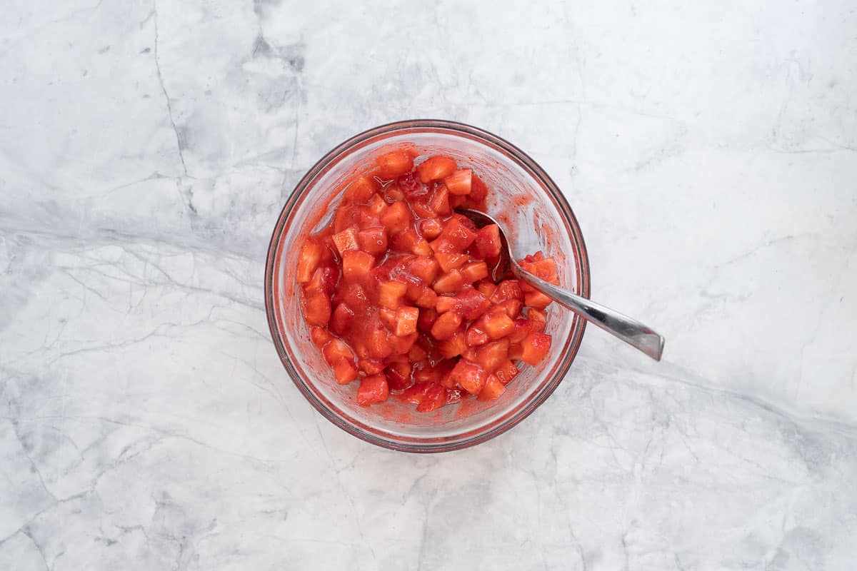 A bowl of strawberry puree stirred through diced strawberries.